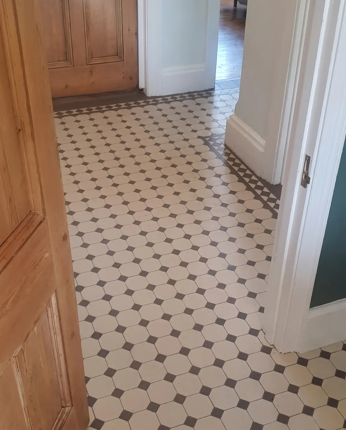 Victorian style black and white geometric mosaic floor laid in a hallway
